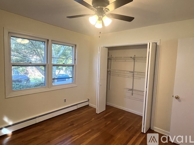 A room with a ceiling fan and a large window.