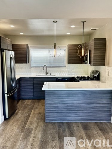 A modern kitchen with a refrigerator, sink, and cabinets.