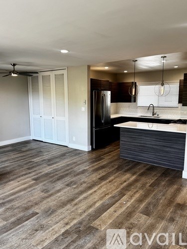 A kitchen with a wooden floor and a refrigerator.