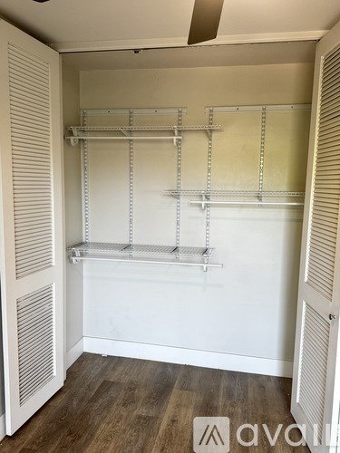 A white pantry with shelves and a wooden floor.