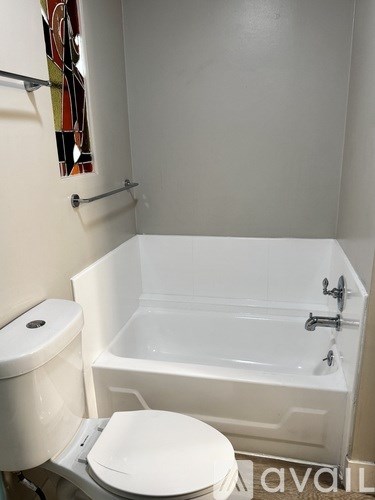 A white toilet sits next to a white bathtub in a bathroom.