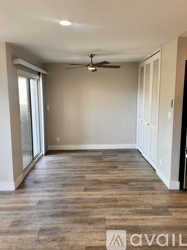 A room with a ceiling fan and a sliding glass door.