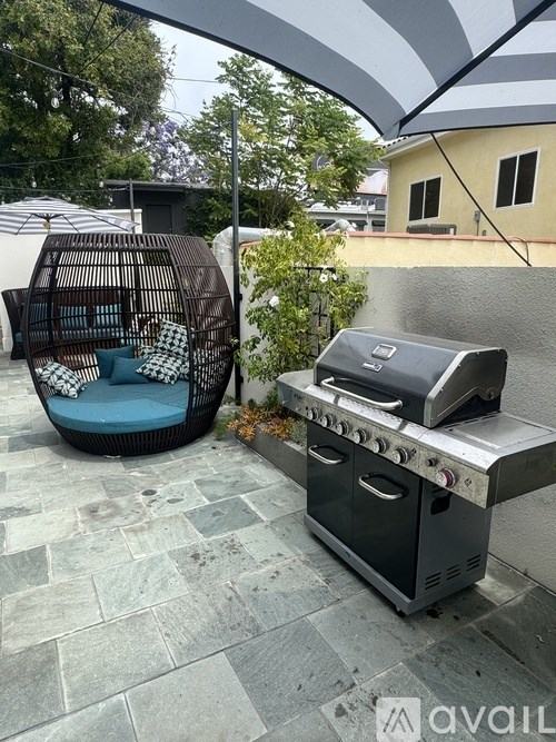 A patio with a grill and a wicker chair.