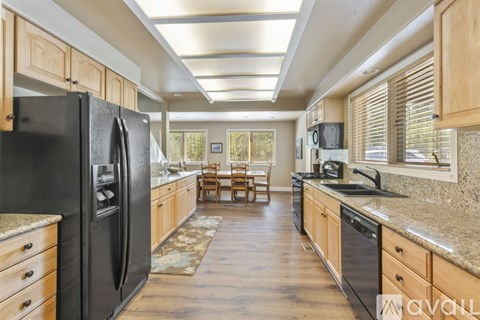 A kitchen with a black fridge and wooden cabinets.