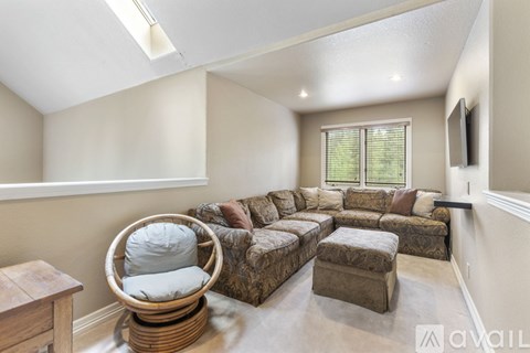 A living room with a large sectional sofa and a wicker chair.