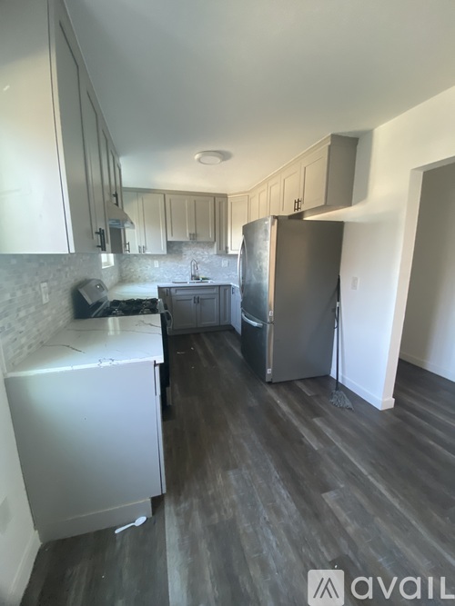 A kitchen with a refrigerator, sink, and cabinets.