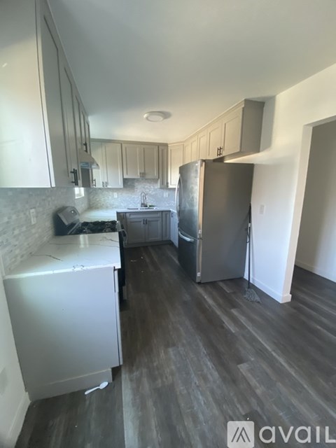 A kitchen with a refrigerator, sink, and cabinets.