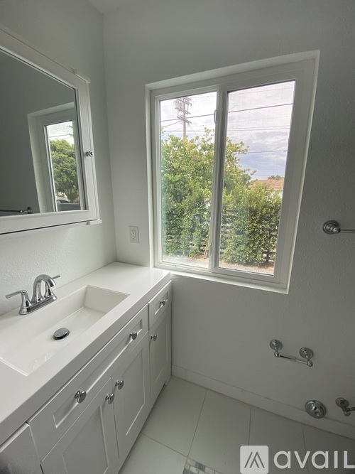 A bathroom with a window overlooking a tree-filled landscape.