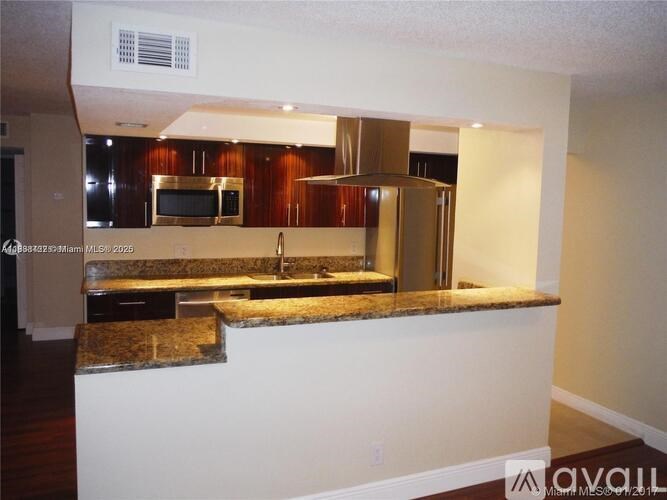 A kitchen with a granite countertop and stainless steel appliances.