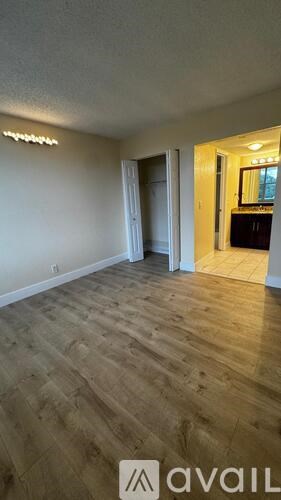 A room with wooden flooring and a doorway leading to another room.