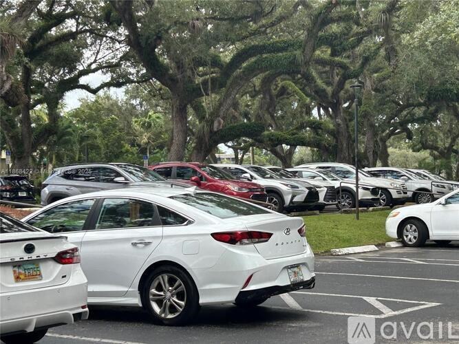A white car is parked in a lot with other cars.