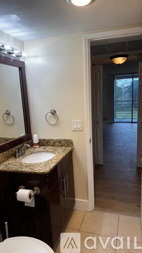 A bathroom with a sink, mirror, and toilet paper roll.