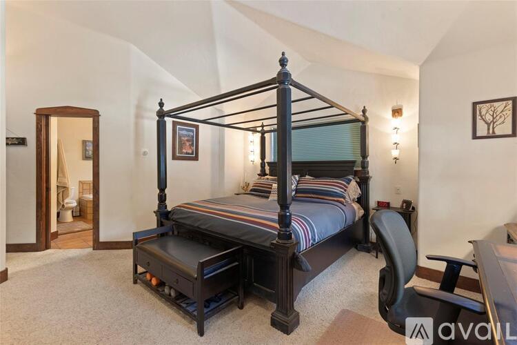 A bedroom with a four poster bed and a chair.