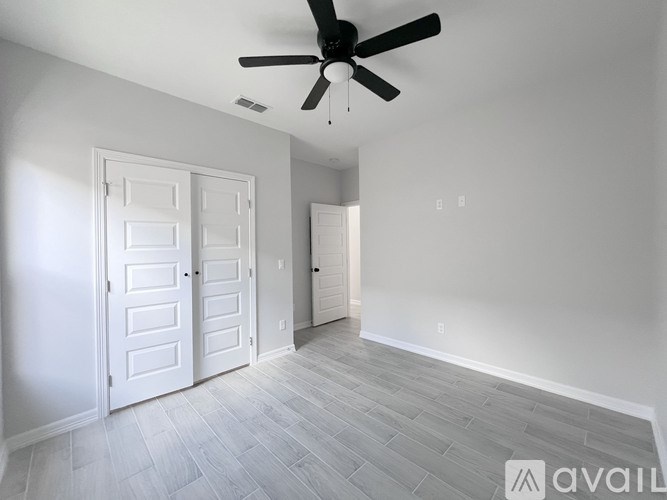 A spacious room with a ceiling fan and two doors.