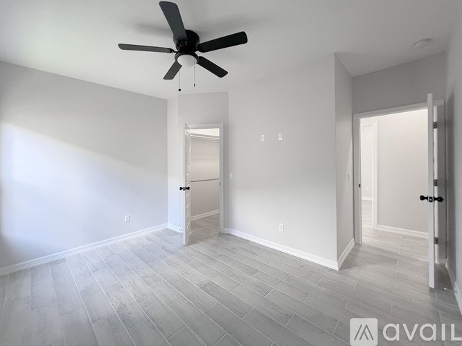 A spacious room with a ceiling fan and light wood flooring.