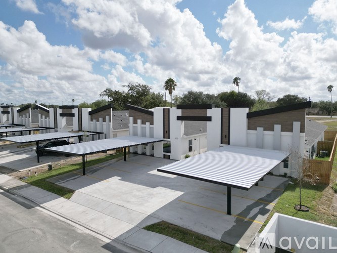 A parking lot with a white canopy and a building in the background.