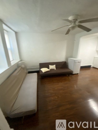 A living room with a couch, a fan, and a cabinet.