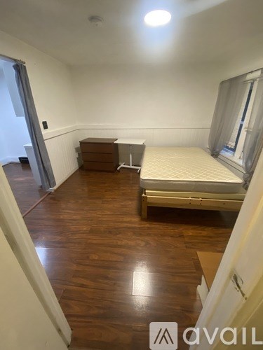 A bedroom with a bed, dresser, and window.