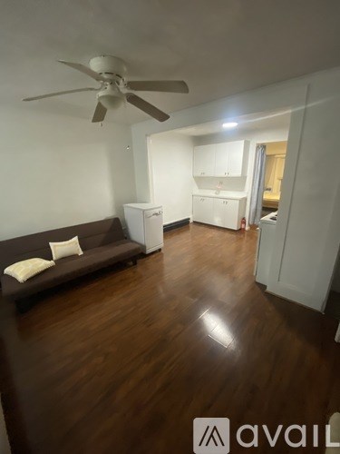 A living room with a brown couch and a ceiling fan.