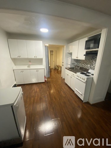 A kitchen with white cabinets and a wooden floor.