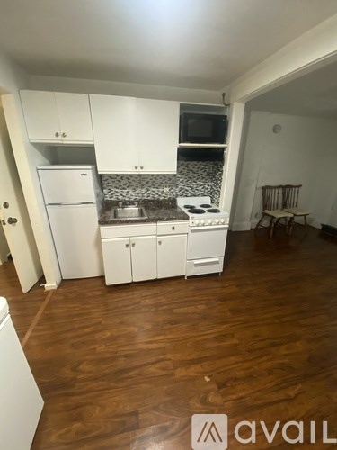 A kitchen with white cabinets and a wooden floor.