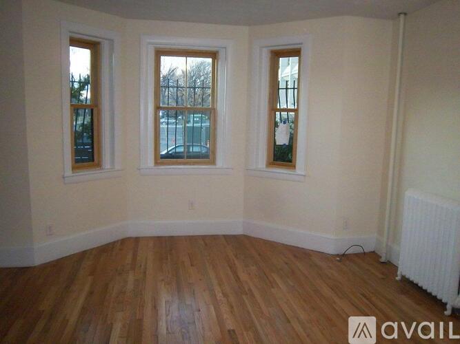 A room with wooden floors and three windows.