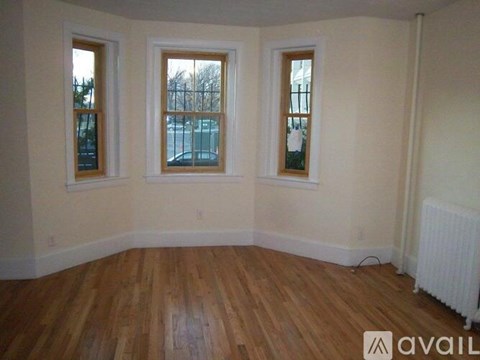 A room with wooden floors and three windows.