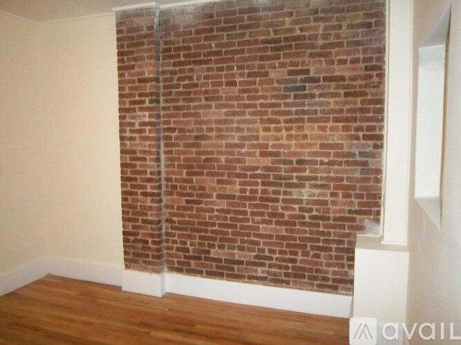 A room with a brick wall and wooden floor.