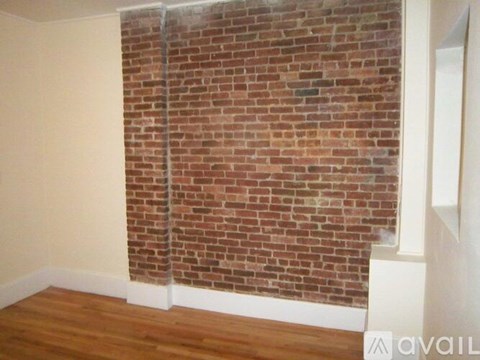 A room with a brick wall and wooden floor.