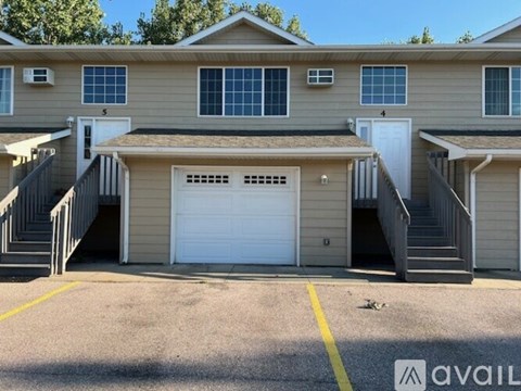 A two-story house with a garage and a staircase leading to the entrance.