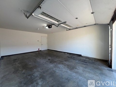 A spacious room with a ceiling fan and a window with curtains.