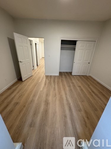 A room with wooden flooring and two white doors.