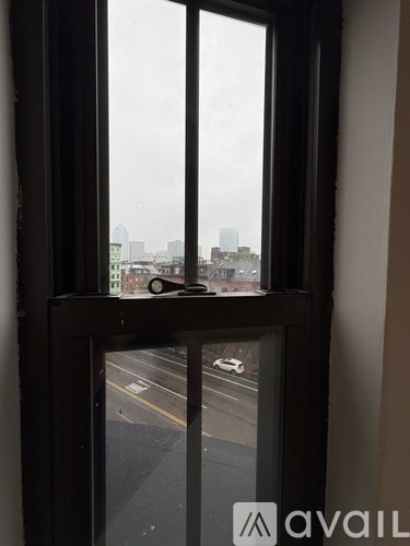 A window with a view of a cityscape and cars on the road.