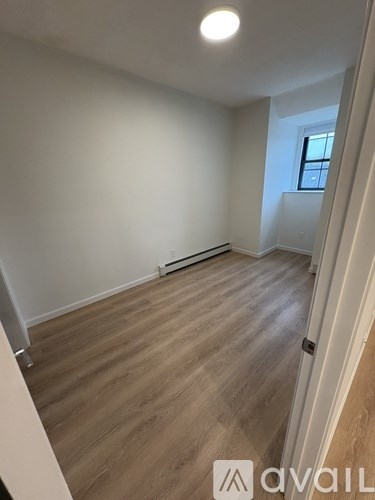 A room with wooden flooring and a window on the right side.