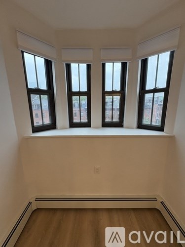 A room with three windows and wooden floors.