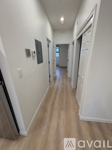 A long hallway with white walls and wood flooring.