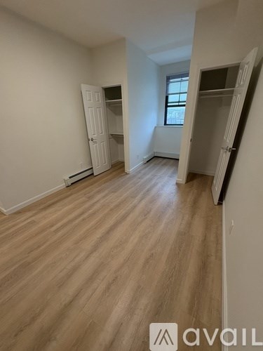 A room with wooden flooring and two open closets.