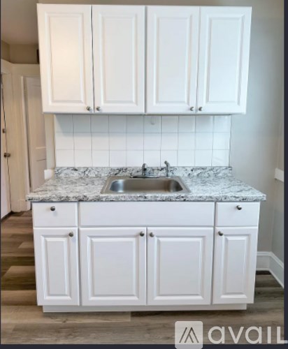 A kitchen with white cabinets and a marble countertop.