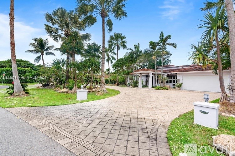 A house with a driveway and palm trees in front.