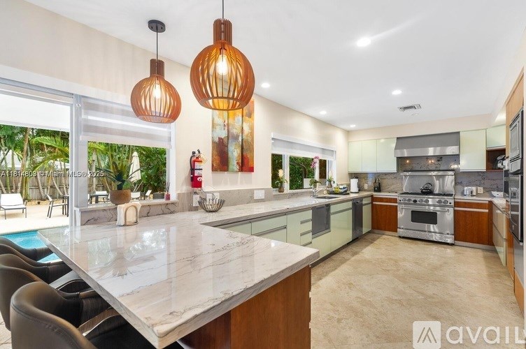 A modern kitchen with a marble island and pendant lights.
