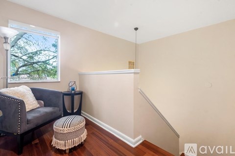 A living room with a grey couch and a woven stool.