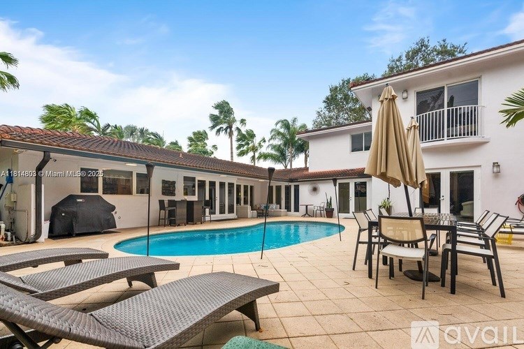 A poolside patio area with lounge chairs and an umbrella.