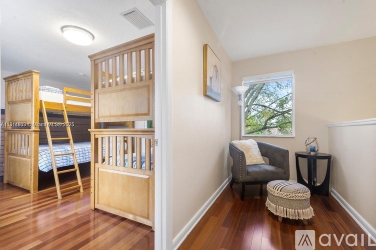 A room with wooden bunk beds and a chair with a cushion.