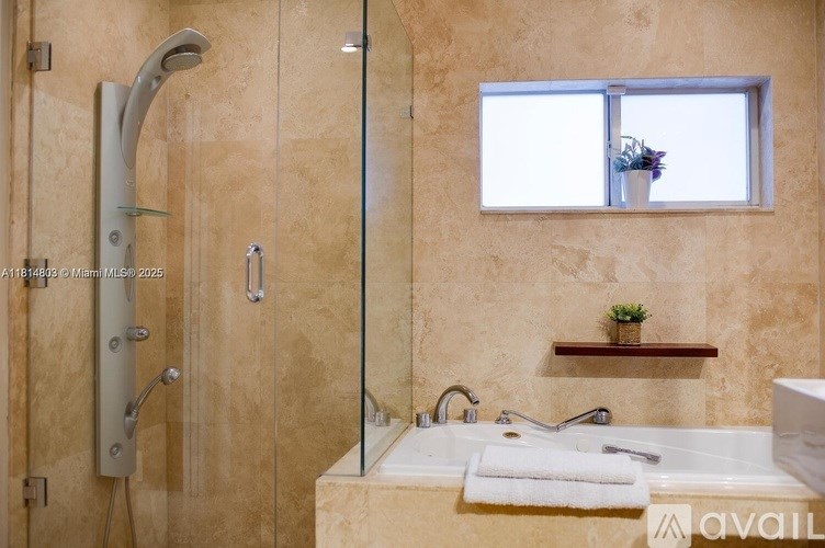 A bathroom with a glass shower door, a bathtub, and a window.