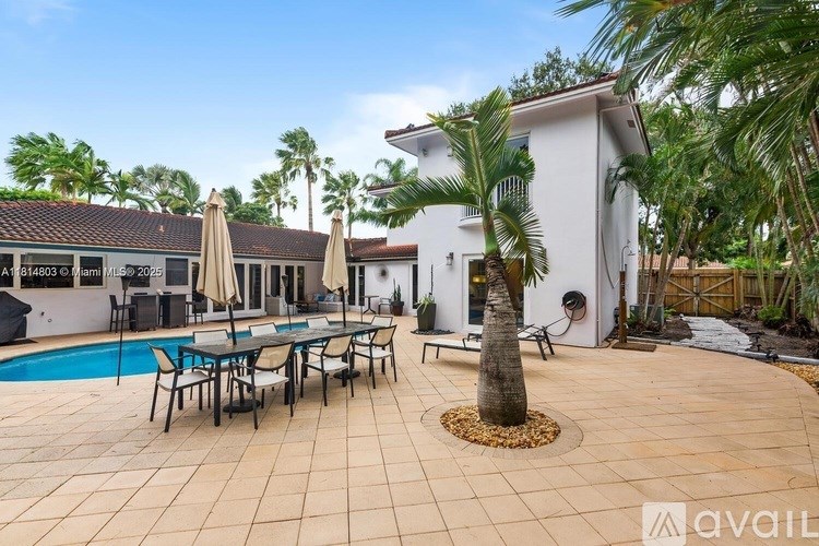 A poolside area with a table and chairs and a palm tree.
