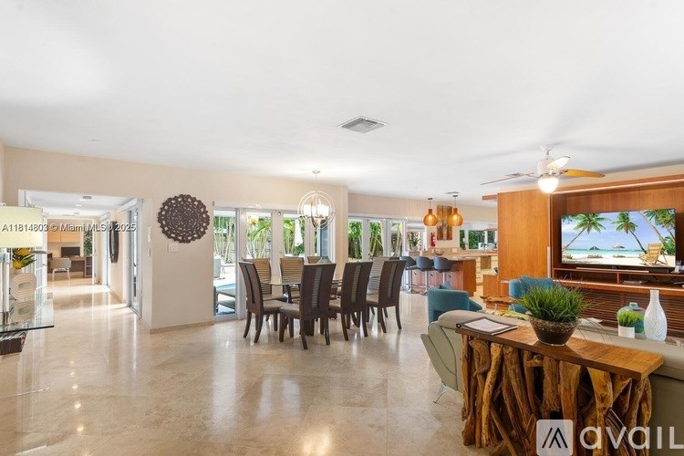 A spacious living room with a dining table set up and a view of the beach through the window.