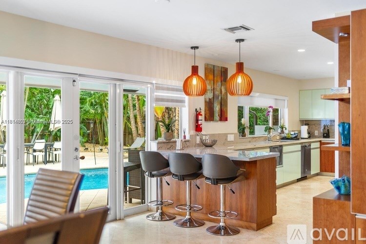 A kitchen with a bar stool and a pool outside.