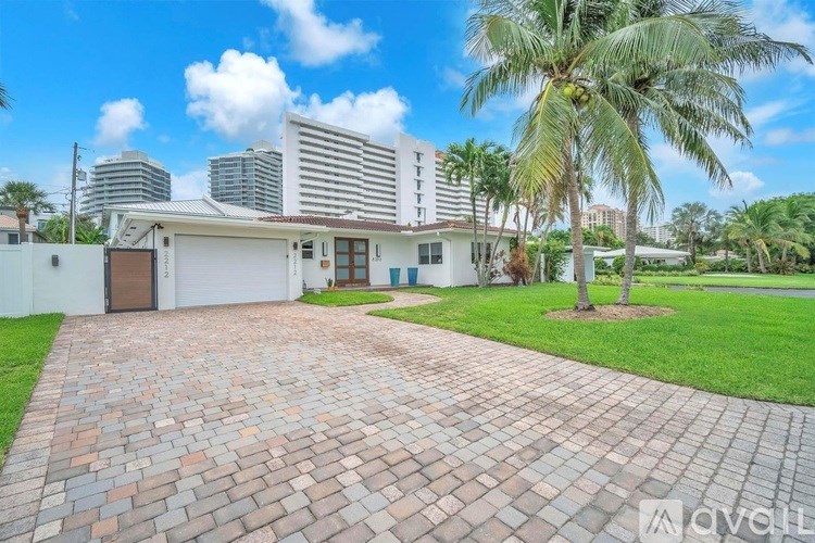 A house with a driveway and palm tree in front of a city skyline.