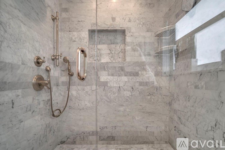 A bathroom with a marble wall and a shower with a glass door.