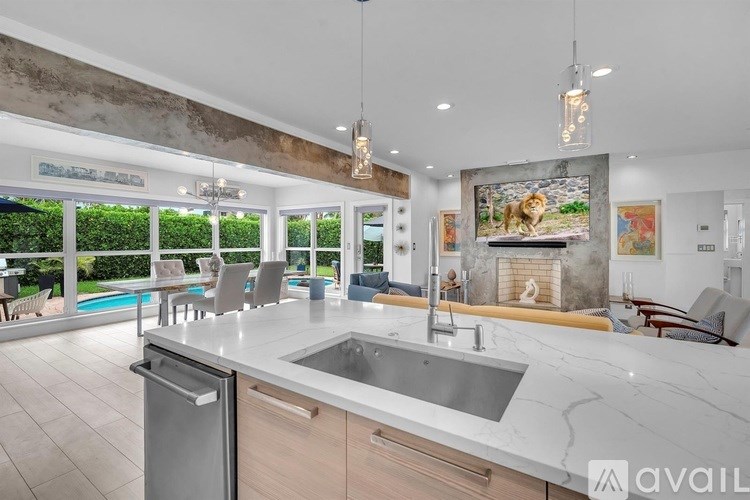 A modern kitchen with a marble countertop and a large window overlooking a pool.